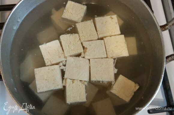 Тофу нарезаем средним кубиком. Теперь его нужно бланшировать. Это делается, чтобы прогреть тофу перед жаркой и убрать запах и привкус соевых бобов. Заливаем тофу водой, чтобы покрывала полностью, и ставим на огонь. Как только вода начнет закипать, сливаем тофу.