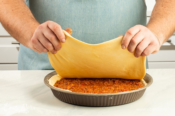 Раскатайте третью часть теста в пласт толщиной 3–5 мм. Накройте начинку этой заготовкой и хорошо скрепите края пирога.