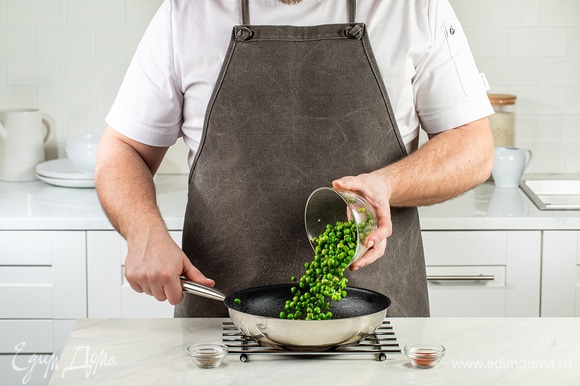 В эту же сковороду добавьте оставшееся оливковое масло и замороженный зеленый горошек. Посыпьте бобы молотой зирой и паприкой, жарьте в течение 5–7 минут.