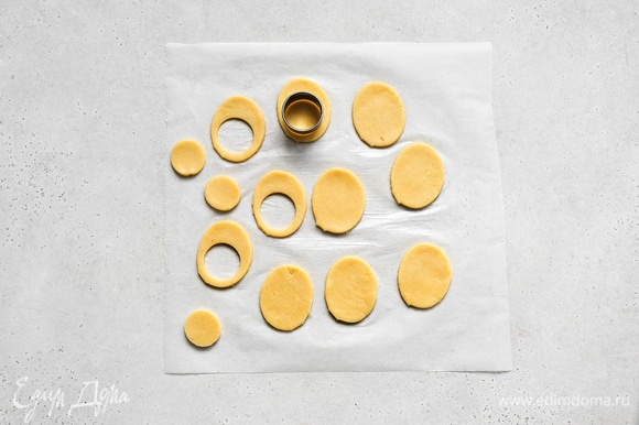 Тесто раскатайте в пласт толщиной 0,5 см. Вырежьте печенье в форме яйца. В половине заготовок сделайте круглые дырочки диаметром, равным диаметру персиков.