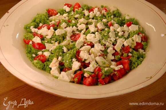 Кускус разрыхлить вилкой и выложить в большое блюдо, полить зеленой заправкой и частью оливкового масла, все посолить и перемешать. Добавить помидоры, еще раз перемешать, разложить сверху фету и полить оставшимся оливковым маслом.