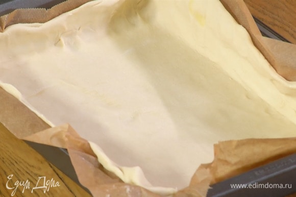 Тесто предварительно разморозить, затем раскатать на бумаге для выпечки в тонкий пласт и вместе с бумагой выложить в небольшую форму.