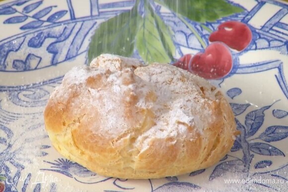 Готовые профитроли начинить кремом и посыпать сахарной пудрой.